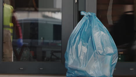 Un-Hombre-Recoge-Una-Bolsa-De-Basura-Dejada-En-La-Puerta-De-La-Casa