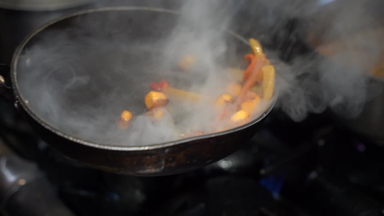 cocinar verduras en una sartén humeante en cámara lenta