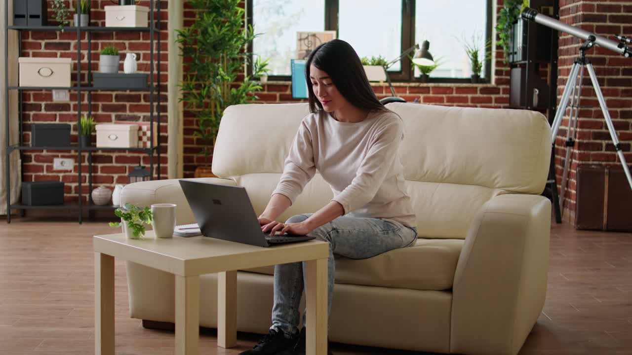 Woman working on laptop at home on couch