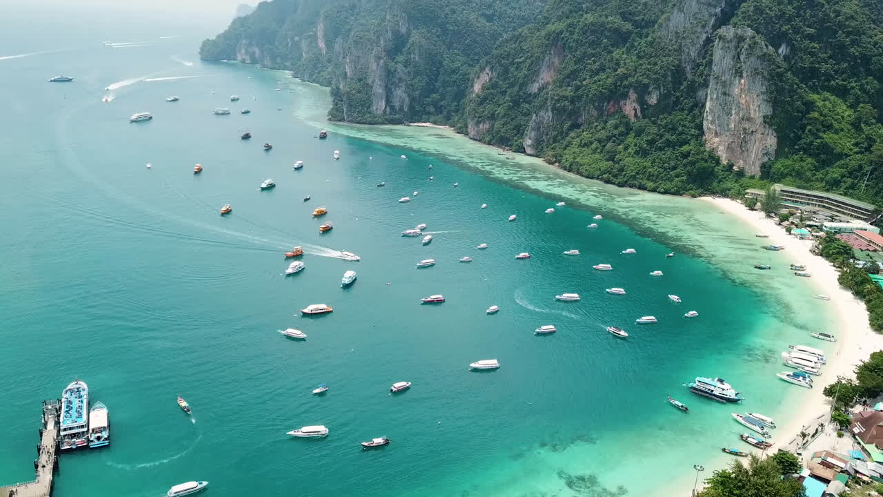 Vista aerea cinematografica con drone della baia dell'isola di Phi Phi Don, scogliere e barche nelle acque turchesi del mare, Krabi, Thailandia.