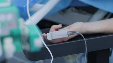 girl's hand with a pulse oximeter in the operating room. modern medical technology for measuring pulse called pulse oximeter on the finger of a woman. hospital tools and equipment.