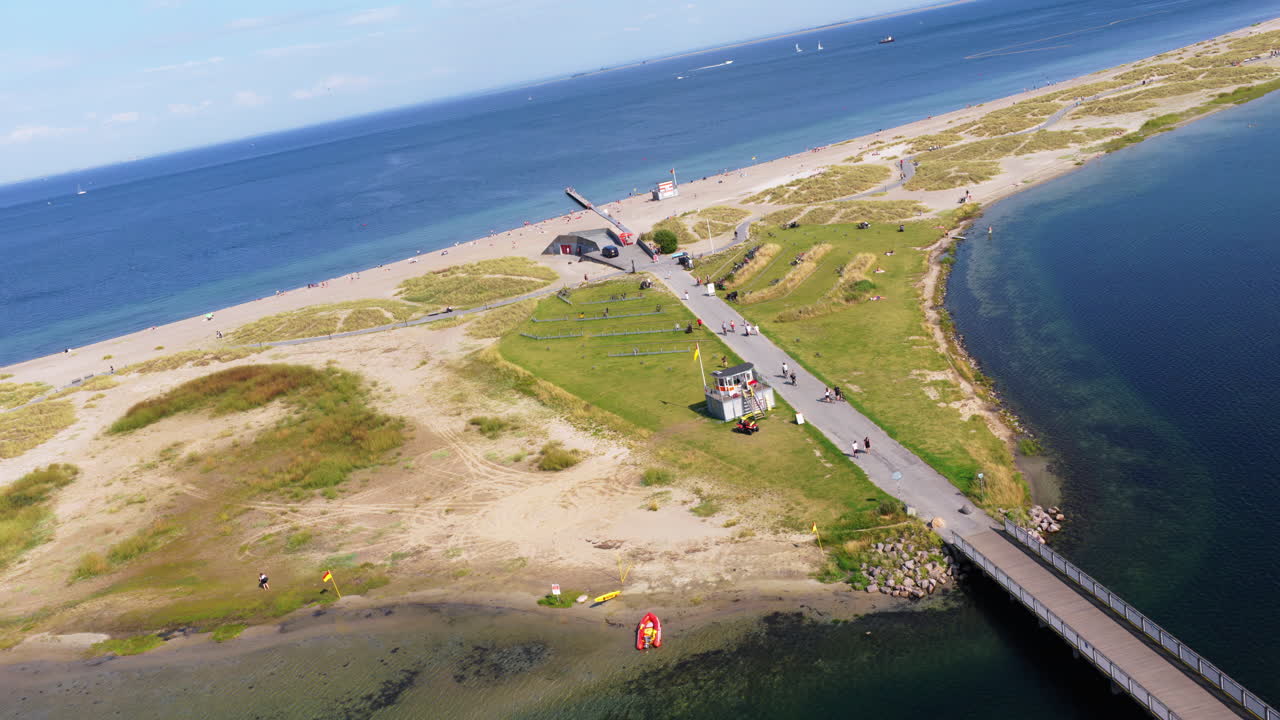 Aerial drone view of Amager Strandpark beach and promenade, with people sunbathing and walking along the pier