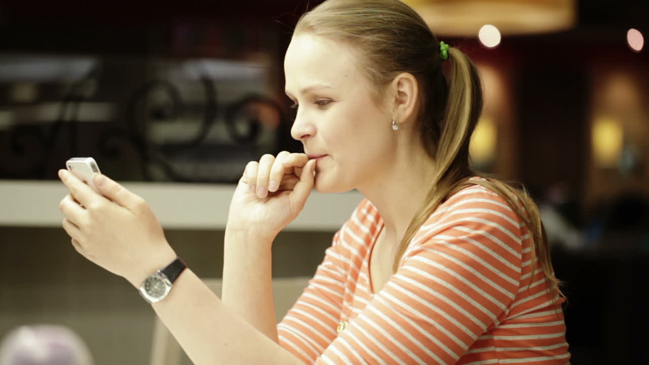 Junge schöne Frau chattet im Café auf dem Smartphone