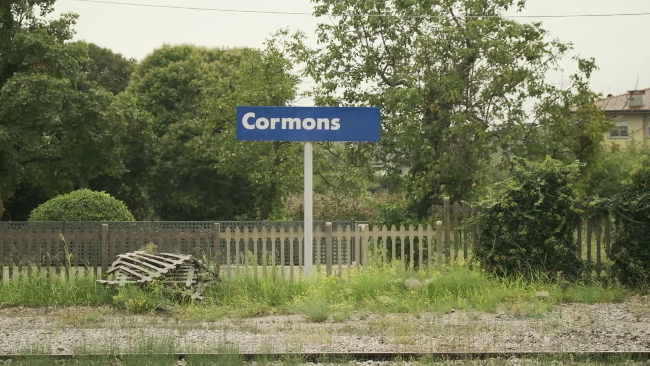 A small countryside train station surrounded by fields in rain