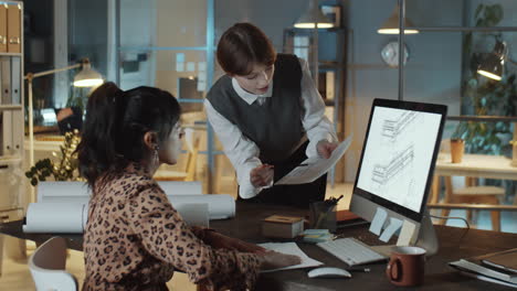 diverse female colleagues working on architectural plan in night office