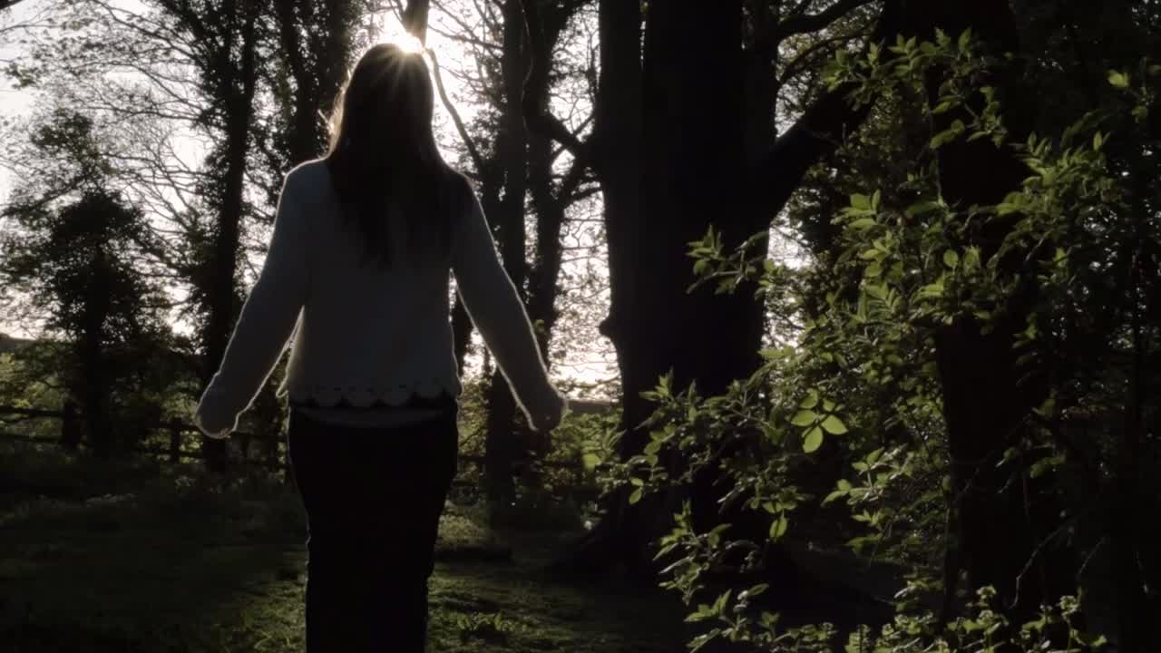 Woman walking in a forest at sunset