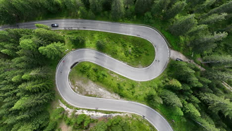 cyclists riding curving alpine woodland forest road aerial top down view