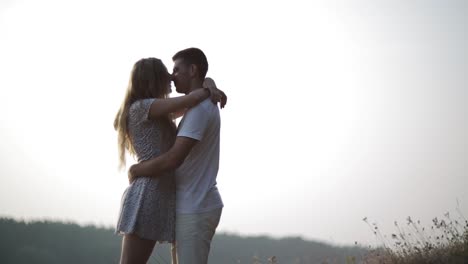 young couple walk to river bank. young couple in love holding hands watching sunrise together outdoors by the lake