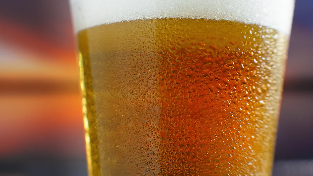 la cerveza se está vertiendo en un vaso angulado. ipa en el grifo. cerveza ligera fría en un vidrio con gotas de agua. cerveza artesanal formando olas de cerca. frescura y espuma. fondo de bar. cerveza artesanal de microbrewery.