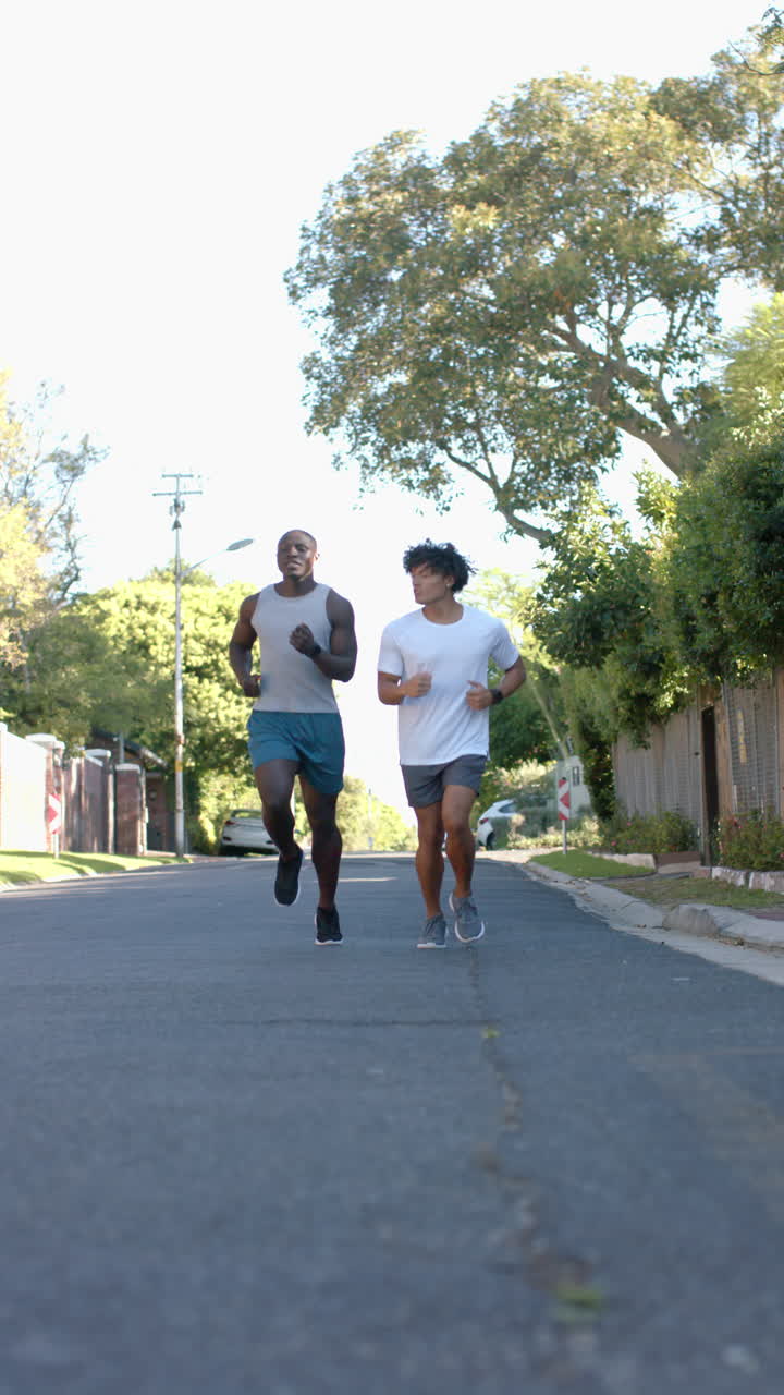 Vertical video: Two men jogging outdoors on sunny day, enjoying fitness and friendship