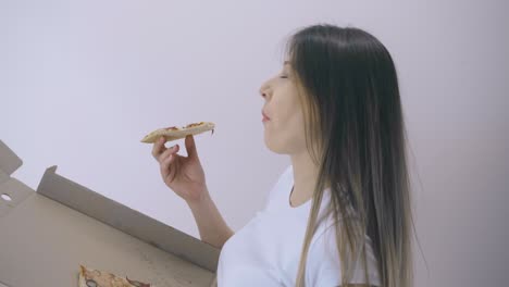 pregnant lady eats pizza from box on white backgrounder