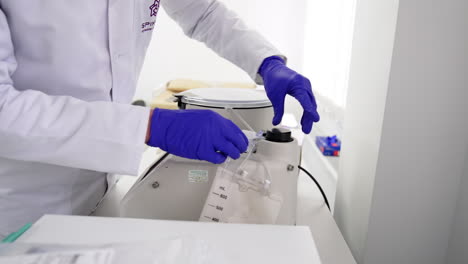doctor in white robe stands at the medical equipment. unrecognized medic preparing device for blood sampling. prp-therapy concept.
