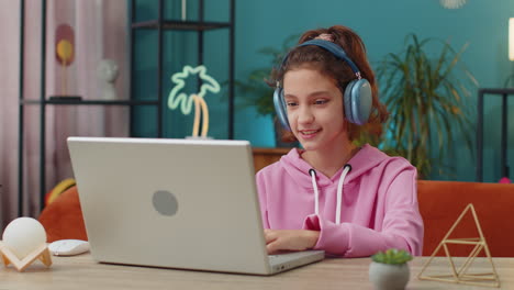 school girl looking at laptop camera, making video webcam conference call with friends or teacher