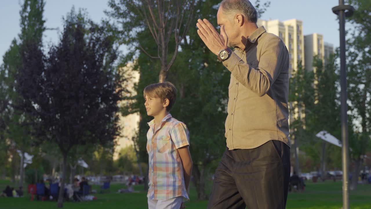 un niño y un anciano caminando por el parque.