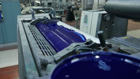 blue paint pot with a roll behind preparing to print some templates for the labels, mass production machine