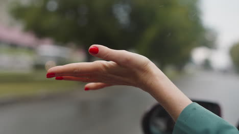 mujer feliz extiende la mano por la ventana del coche para atrapar la lluvia