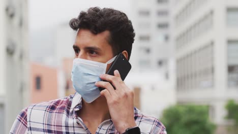 Caucasian-man-wearing-a-coronavirus-Covid19-mask-and-having-a-phone-call