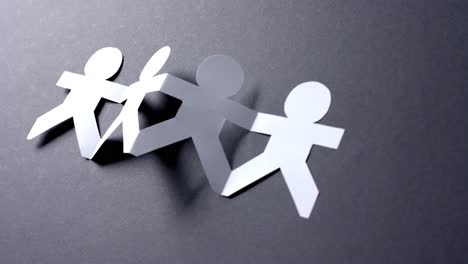 close up of people holding hands made of white paper on gray background with copy space