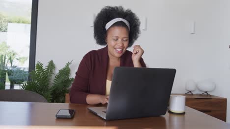 African-american-plus-size-woman-sitting-at-table-and-using-laptop,-unaltered,-slow-motion