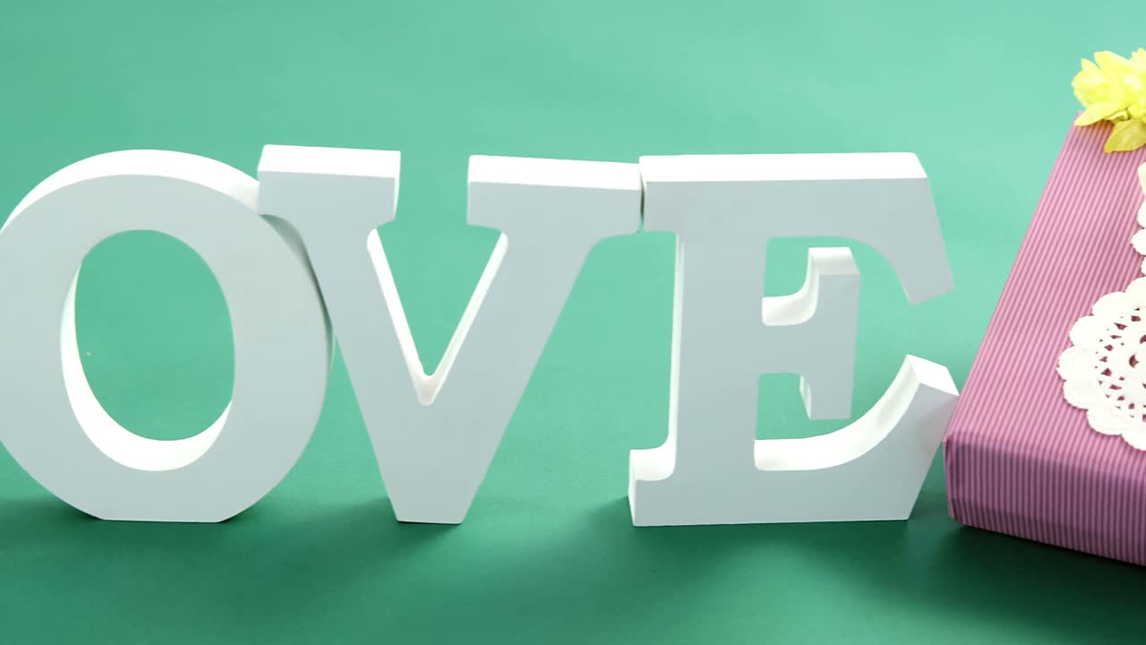 Gift box and alphabet love on green background