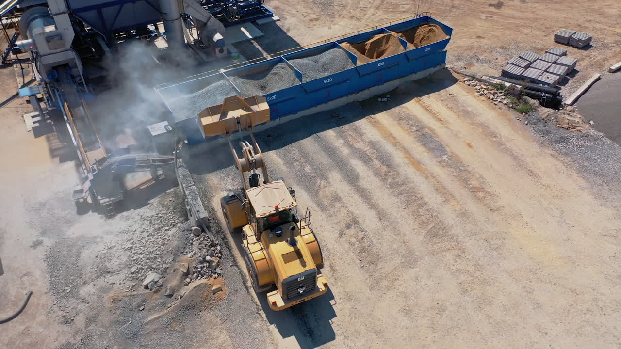 Bulldozer working with gravel outdoors. Industrial machine carrying rubble into into special containers. Asphalt factory. Aerial view.