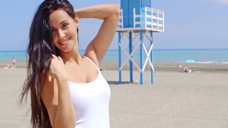 brunette woman on beach shading eyes with hand