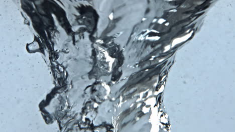 agua girando vidrio transparente de cerca. vórtice líquido de hielo con burbujas de aire