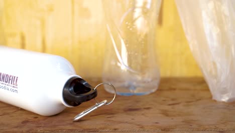 Close up of refill white bottle on the wood table against plastic bottle and plastic bag . Concept global environment protection.