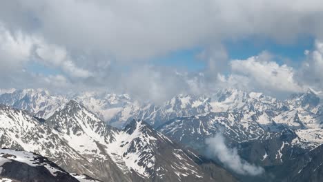 air flight through mountain clouds over beautiful snow-capped peaks of mountains and glaciers.