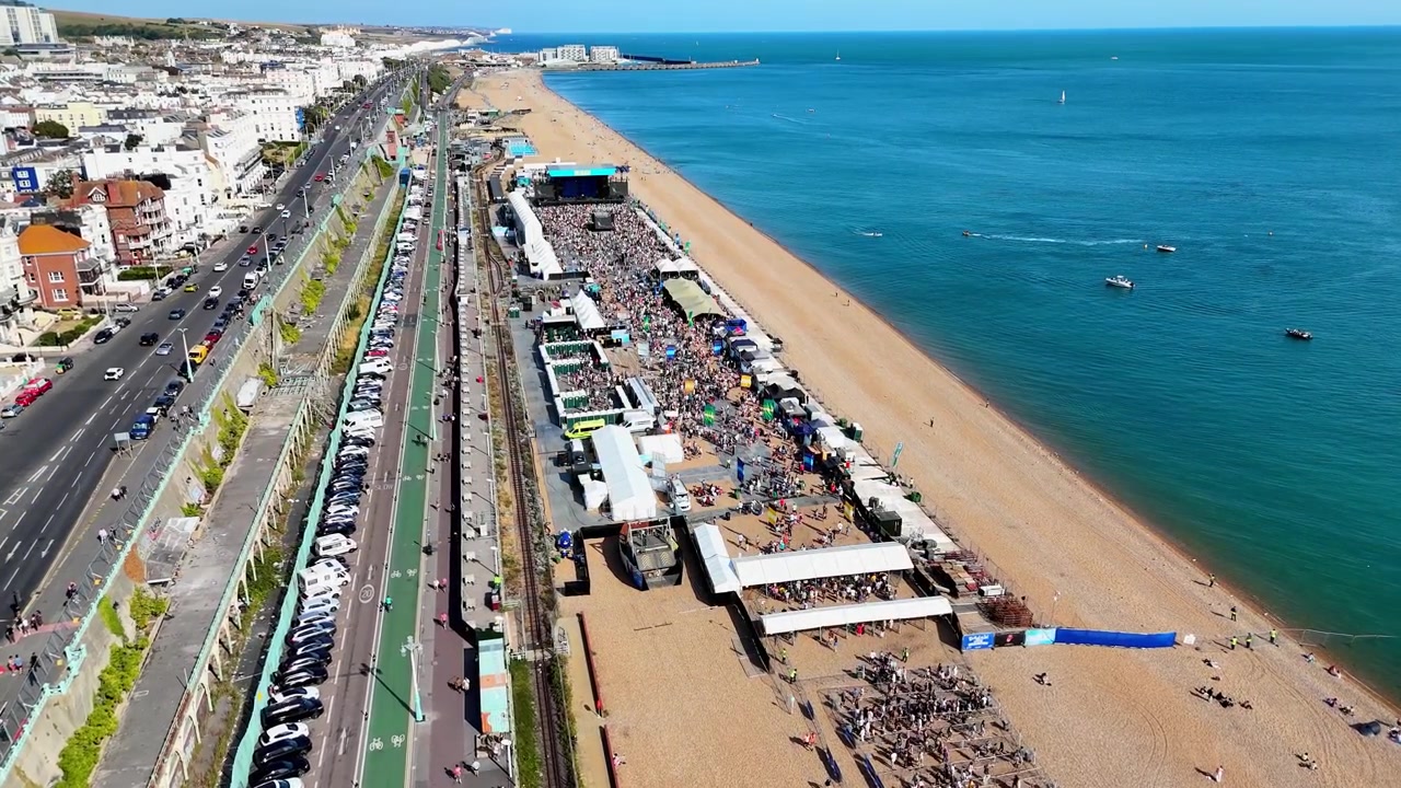 Brightonin ranta kesämusiikkifestivaalien aikaan, täynnä ranta-alueen väkeä, vilkkaita rantoja ja veneitä merellä Sussexin rannikolla. Ilmakuva.