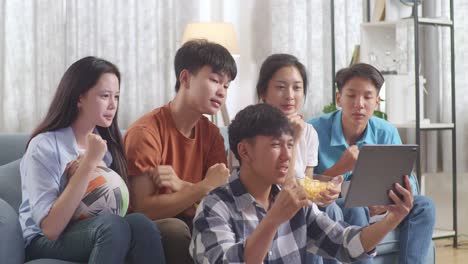 asian teenagers cheering and watching football game on tablet. team celebrating victory and team disappointed