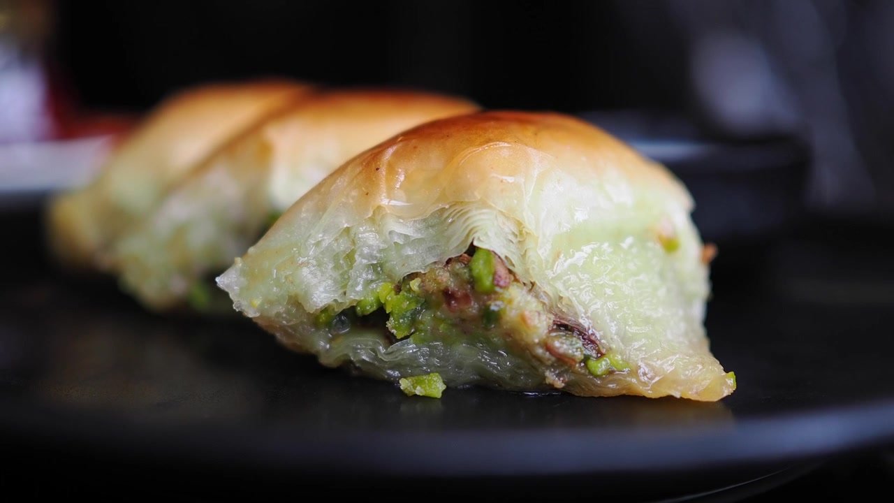 Primo piano di baklava tradizionale al pistacchio su un piatto nero