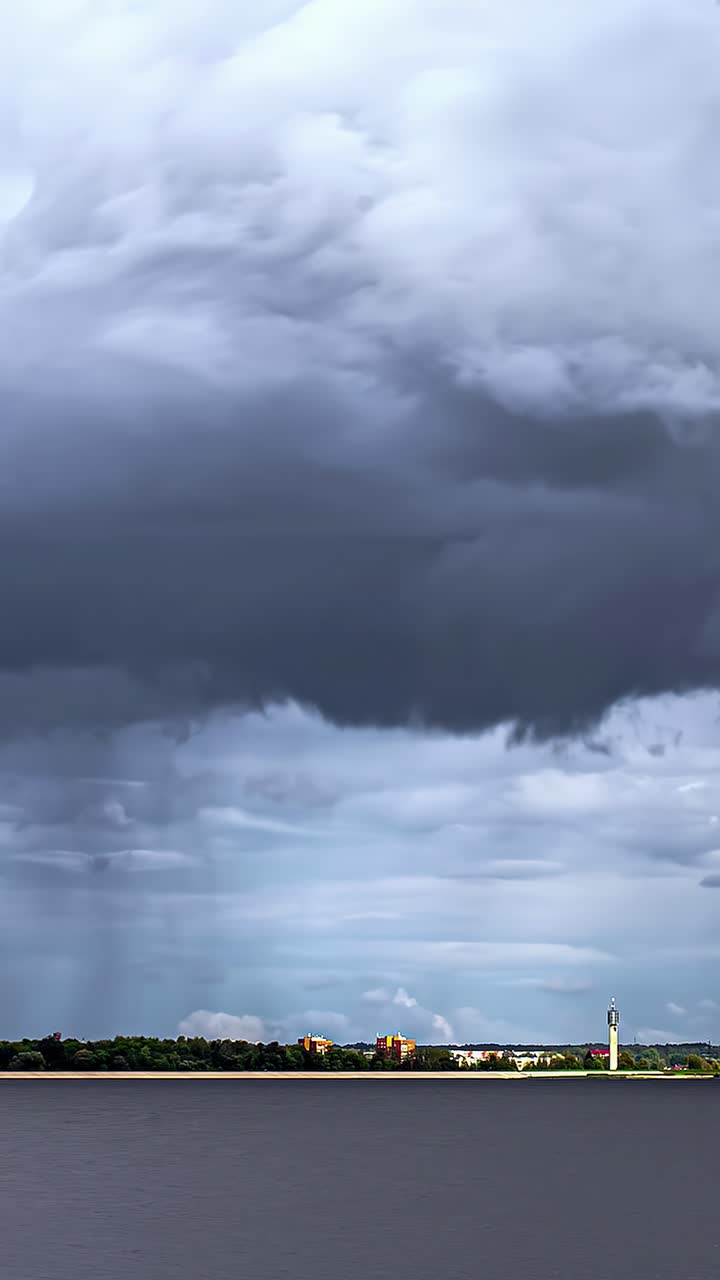 Profile view of dense, thick clouds moving prior to rainfall over a river. Time lapse shot