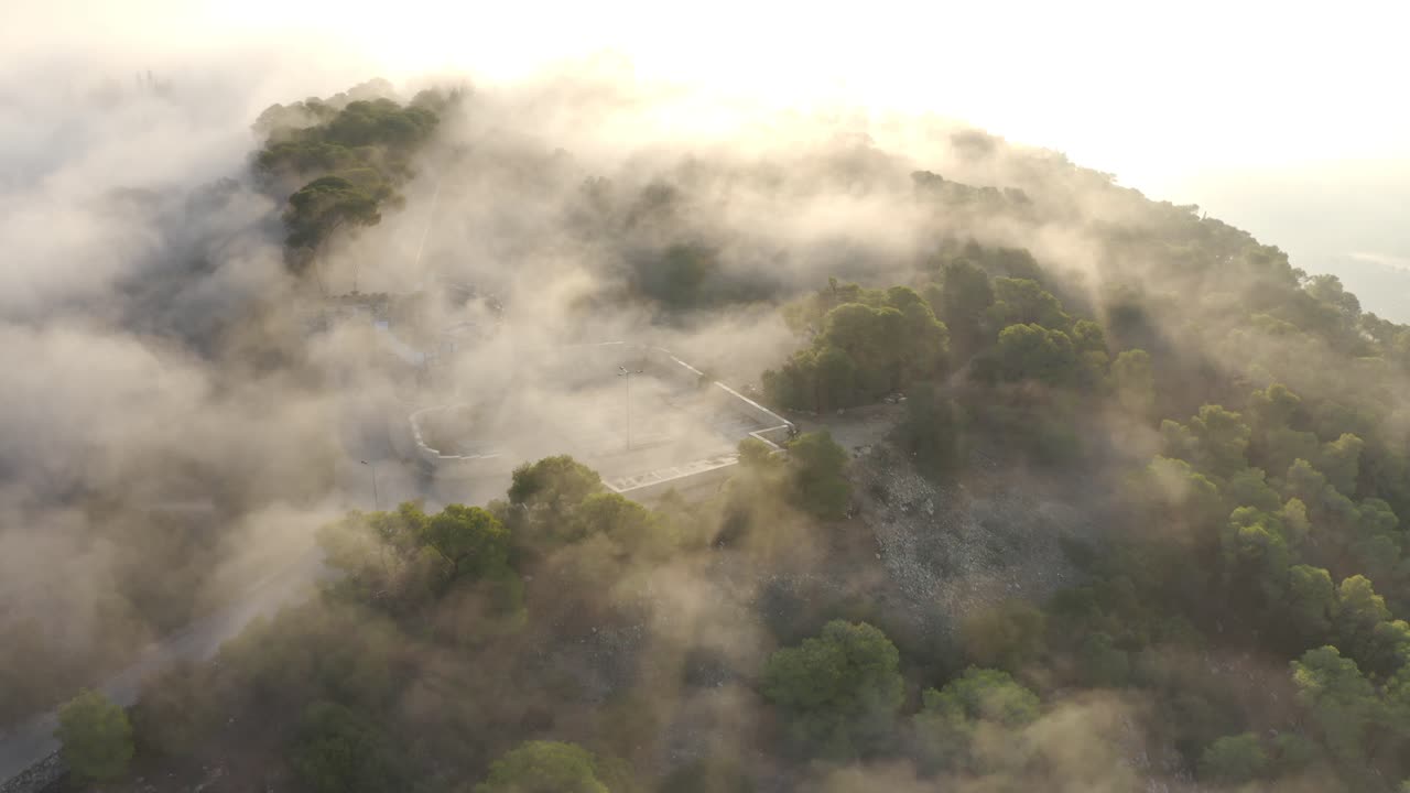 산악 지형 위의 안개가 가득한 해가 뜨는 모습