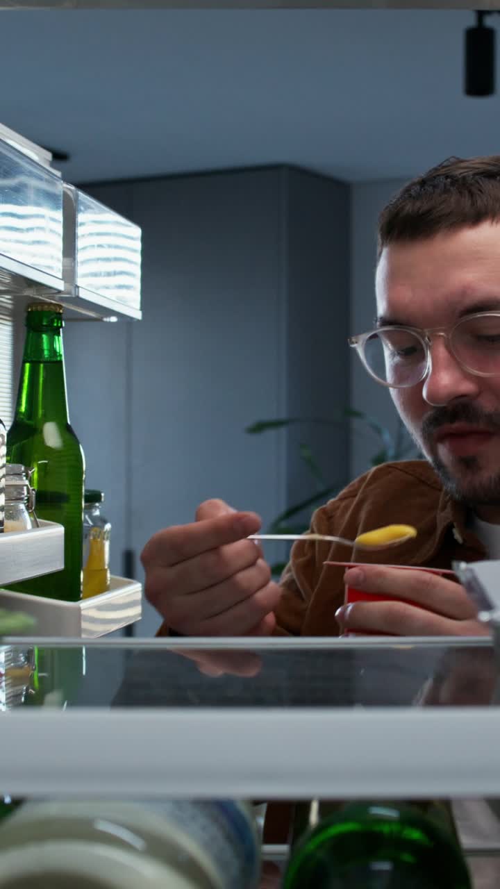 hombre buscando comida en el refrigerador por la noche