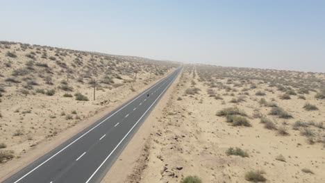 aerial drone shot showcasing the vastness of the desert as a lone bike cruises down the center of the road.