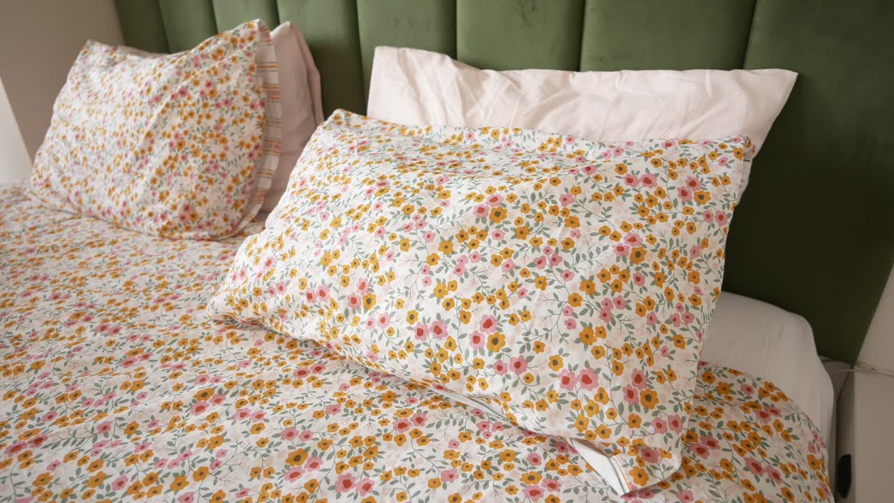 cerca de una cama con ropa de cama floral y almohadas