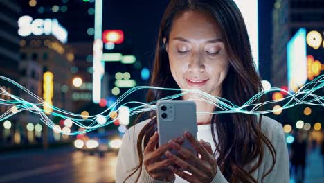 woman using a smartphone in a city at night