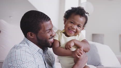 father playing with baby daughter tickling her at home