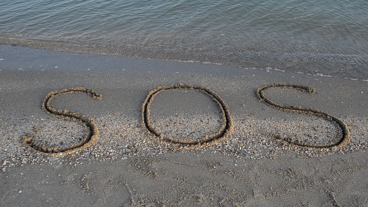 The inscription SOS on sand. Shooting on the beach