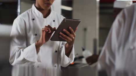chef afroamericana que usa una tableta en la cocina de un restaurante