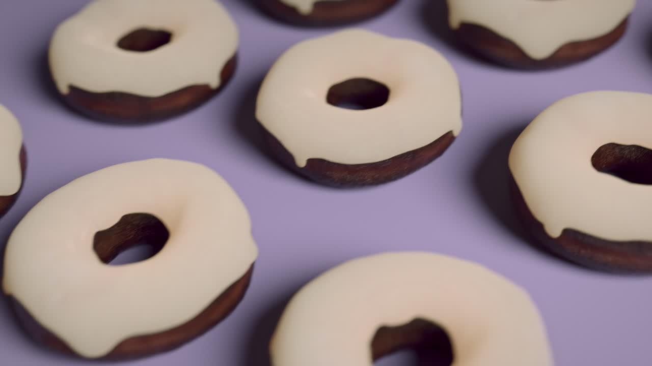 White glaze donuts on a light violet background