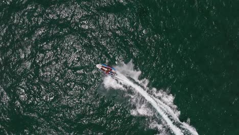 extreme jet boat roaring across the sea with tourists, aerial footage