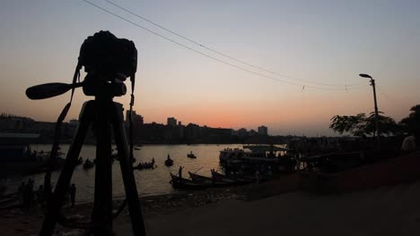 silhouette of a camera and tripod shooting the dusk sunset at buriganga river in dhaka, bangladesh