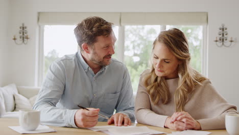 excited couple sitting at table at home signing financial document