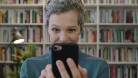 portrait of mature friendly caucasian woman librarian texting browsing using smartphone social media app reading text message surprised expression