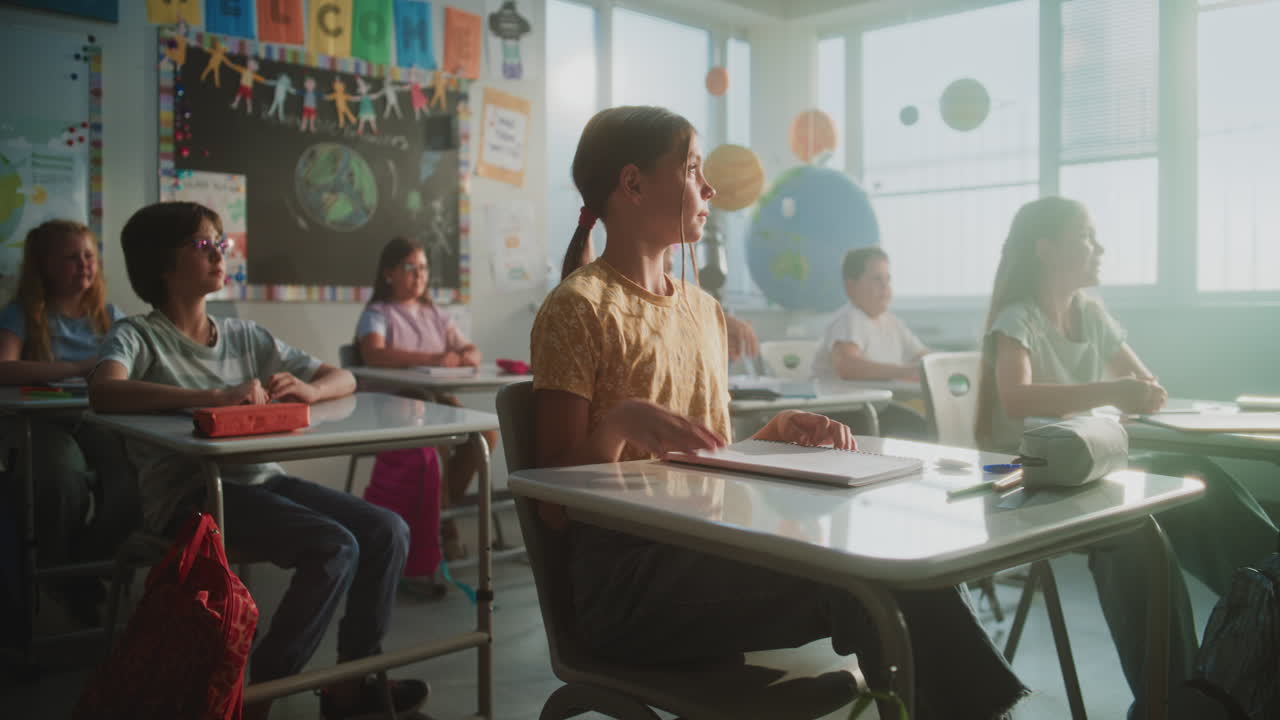 Primary School Children Sitting at Desks Writing School Exam or Doing Tasks in Notebooks
