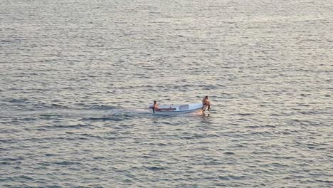 barco pasando por el mar con un hombre sentado en la parte delantera del barco