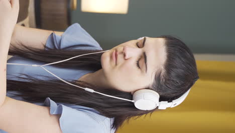 vertical video of woman listening to music with headphones is unhappy and sad.