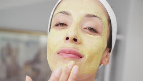 portrait of caucasian woman looking in mirror and doing make up in bathroom